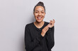 Horizontal shot of cheerful pretty Latin woman rubs palms and laughs joyfully hears funny joke from friend expresses positive sincere emotions wears black jumper isolated over white background