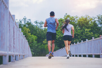 Canvas Print - Young couple running together on road across the bridge. Couple, fit runners fitness runners during outdoor workout.