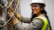 A focused female electrician in a yellow safety helmet meticulously works on a complex electrical panel