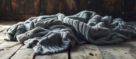 Poster - Warm knitted gray crumpled blanket on a wooden background. Creative Banner. Copyspace image