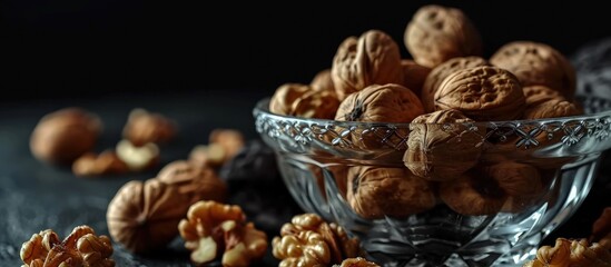 Aufkleber - walnuts in a clear glass bowl and scattered on a black table selective focus. Creative Banner. Copyspace image