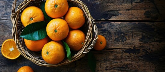 Poster - Top view of fresh orange fruit in the basket and orange leaf on the wooden background. Creative Banner. Copyspace image