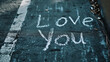 © Synaptic Studio - 'Love You' white chalk written words on the grey dark asphalt
