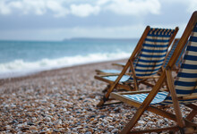 Deck Chairs Are Stacked On A Lovely Pebble Beach, Signifying The End Of The Sea Season And The Closure Of Public Beaches