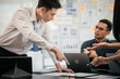 © makibestphoto - diverse group of Asian professionals, including middle-aged and mature individuals, gathered around a table in a business setting, discussing documents with focused attention.