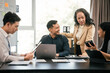 © makibestphoto - diverse group of Asian professionals, including middle-aged and mature individuals, gathered around a table in a business setting, discussing documents with focused attention.