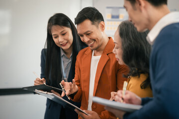 Wall Mural - Asian business professionals team actively engaged in collaborative meeting in boardroom, sharing opinions and working together with visible happiness.