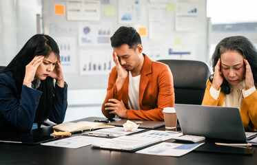 Wall Mural - Asian colleagues in a boardroom, looking at a tablet with excited and joyful expressions, indicating a successful moment rather than stress.