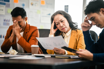 Wall Mural - Asian colleagues in a boardroom, looking at a tablet with excited and joyful expressions, indicating a successful moment rather than stress.