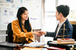 © Phushutter - Asian man and woman collaborating professional setting, law office. reviewing documents on tablet, with laptop, contract papers, law books, and justice scale on the desk.