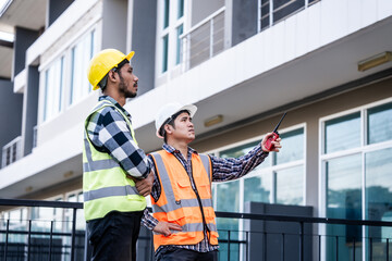 Asian people, two man, holding blueprints Structural engineers examine structural plans for office buildings and housing developments on-site, discussing work at construction site.