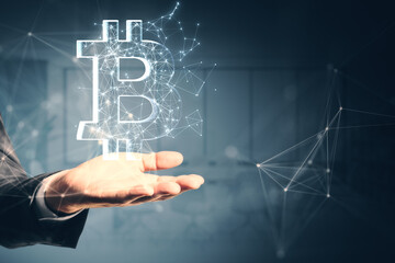Fototapete - Close up of male hand holding creative polygonal bitcoin sign on gray wall background. Online banking, money and trade concept.