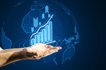 Wall Mural - Close up of male hands holding glowing business chart with globe hologram on blurry background. Financial plan graph.