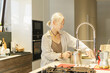 © Westend61 - Mature woman filling steel jug with water in kitchen at home