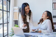 © amnaj - Two young Asian business woman talk, consult, discuss working with new startup project idea presentation analyze plan marketing and investment in the office.