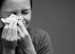 asthmatic breathing problems catching the flu child blowing nose after having a cold with grey background with people stock photo