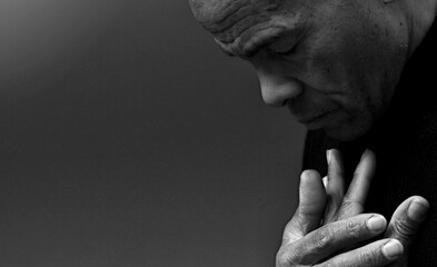 man praying to god with hands together Caribbean man praying with black background with people stock photo