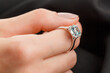 © Minakryn Ruslan  - Beautiful female hand with gold ring with diamonds and emerald on gray background