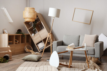 Sofa with tables and shelving units in messy living room