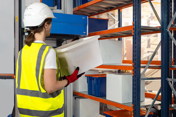 Poster - Woman warehouse worker. Automated storage. Girl near warehouse robot. Storekeeper with container with his back to camera. Storekeeper puts box on rack. Storage worker works together with robot