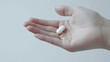 A single white capsule pill rests on the palm of a hand, displayed against a minimalist white background. Panorama with copy space.