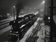 Eine Dampflok fährt im Winter in einen Bahnhof ein