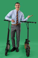 Poster - Handsome businessman with kick scooters on green background