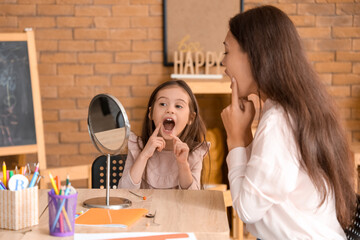 Sticker - Female Asian speech therapist working with little girl at table in office