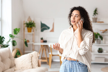 Canvas Print - Young African-American woman talking by mobile phone at home