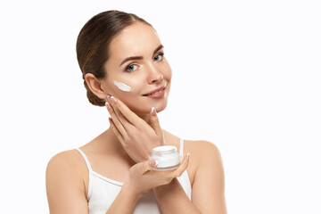 Wall Mural - Beautiful Woman Face Skin Care. Portrait Of Attractive Young Female Applying And Holding Cream Cosmetics And Holding Bottle. Closeup Of Beauty Smiling Girl With Natural Makeup And Fresh Skin