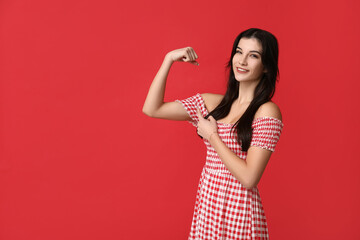 Wall Mural - Young woman flexing muscles on red background. Feminism concept