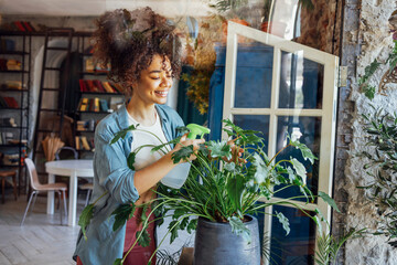 Wall Mural - Young Afro American woman plant lover taking care of houseplant