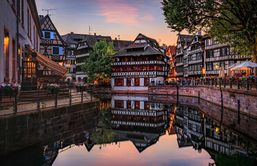 Canvas Print - Ornate traditional half timbered houses with blooming flowers along the canals in the Petite France district of Strasbourg, Alsace, France at sunset