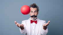A Juggler With A Mustache And A White Jacket Juggles A Red Ball