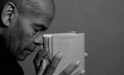 man praying to god with hands together Caribbean man praying with black background with people stock photo