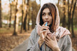Young woman outside autumn park fall and smoking tobacco device electronic cigarette heater. Smoke and steam system with sticks inside, image with copy space. Harmful habit harm to health lungs