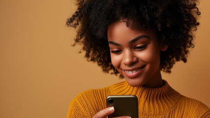 Wall Mural - A young brunette woman is looking at a smartphone screen against a beige monochrome studio background.