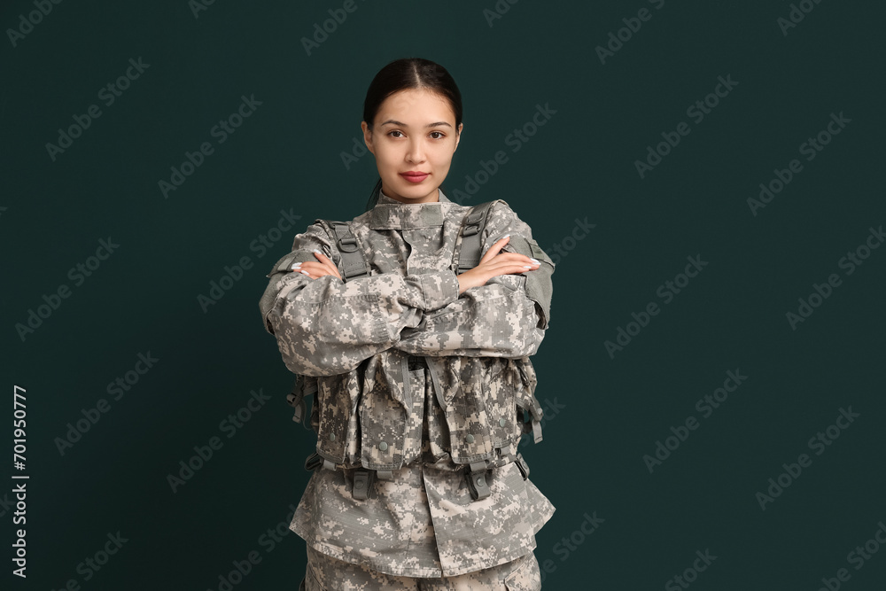 Young female soldier with crossed arms on green background. Feminism concept