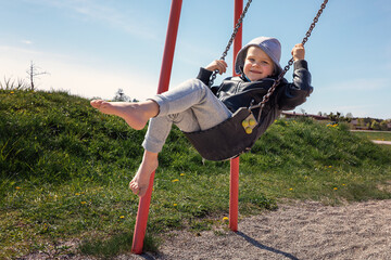 Smiling child on a swing in the field. A carefree childhood is a happy child