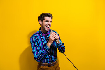 Sticker - Photo of good mood handsome man dressed striped shirt bow tie holding microphone look empty space isolated on yellow color background