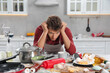 © New Africa - Upset man in messy kitchen. Many dirty dishware, utensils and food leftovers on table