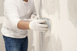 © airdone - Plasterwork and wall painting preparation. Asian male applying filling drywall patch.