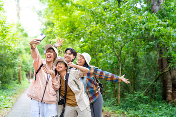 Wall Mural - Group of Young Asian man and woman friends travel nature on summer holiday vacation. Happy people enjoy and fun outdoor lifestyle using digital camera taking picture together at forest mountain.