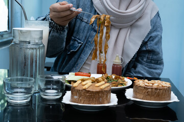 A photo of a hand enjoying a meal with a menu of Kwetiaw noodles, ice cream, water, and a milkshake on the table