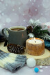 Tea, a candle, a scarf, gift boxes and a fir cone create a cozy atmosphere. Vertical interior poster. Cup of tea with a bag.