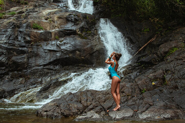 Wall Mural - Beautiful Young Woman in Swimsuit Posing Near Waterfall