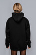 © blackday - Woman dressed in a black oversized hoodie with blank space, ideal for a mockup, set against gray background