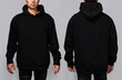 Front and back views of a man wearing a black, oversized hoodie with blank space, ideal for a mockup, set against gray background