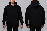 Fototapeta  - Front and back views of a man wearing a black, oversized hoodie with blank space, ideal for a mockup, set against gray background