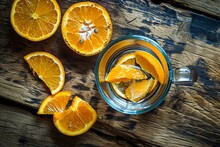 A Glass Of Water With Orange Slices On A Wood Surface